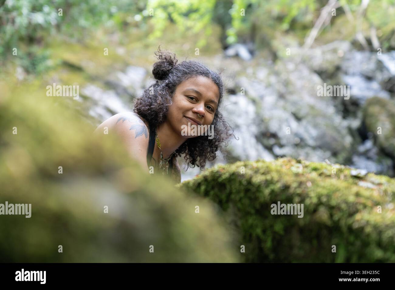 Young woman smiling in nature with waterfall background Stock Photo