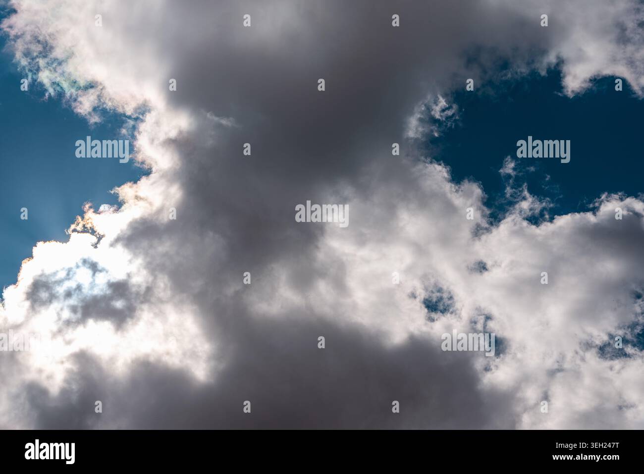 Dramatic dark clouds with sunlight breaking through blue sky. Stock Photo