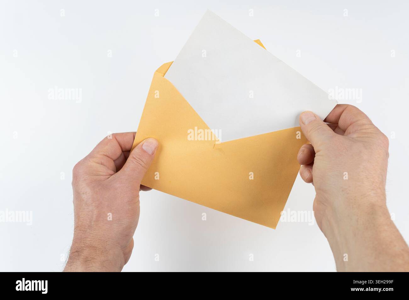 an open yellow envelope in the hands on a white surface Stock Photo