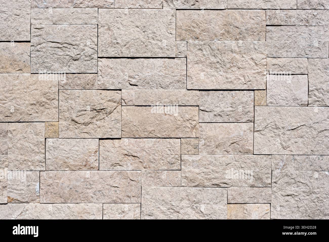 Beige stone wall texture with rectangular blocks and rough natural surface for architecture and construction background. Stock Photo