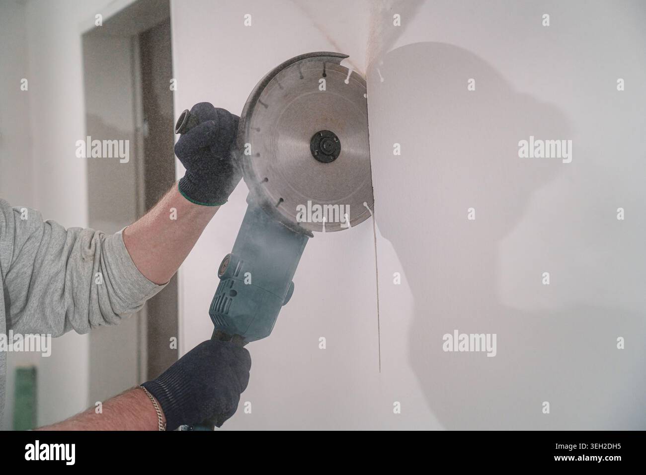 Construction worker cutting concrete wall with angle grinder Stock Photo