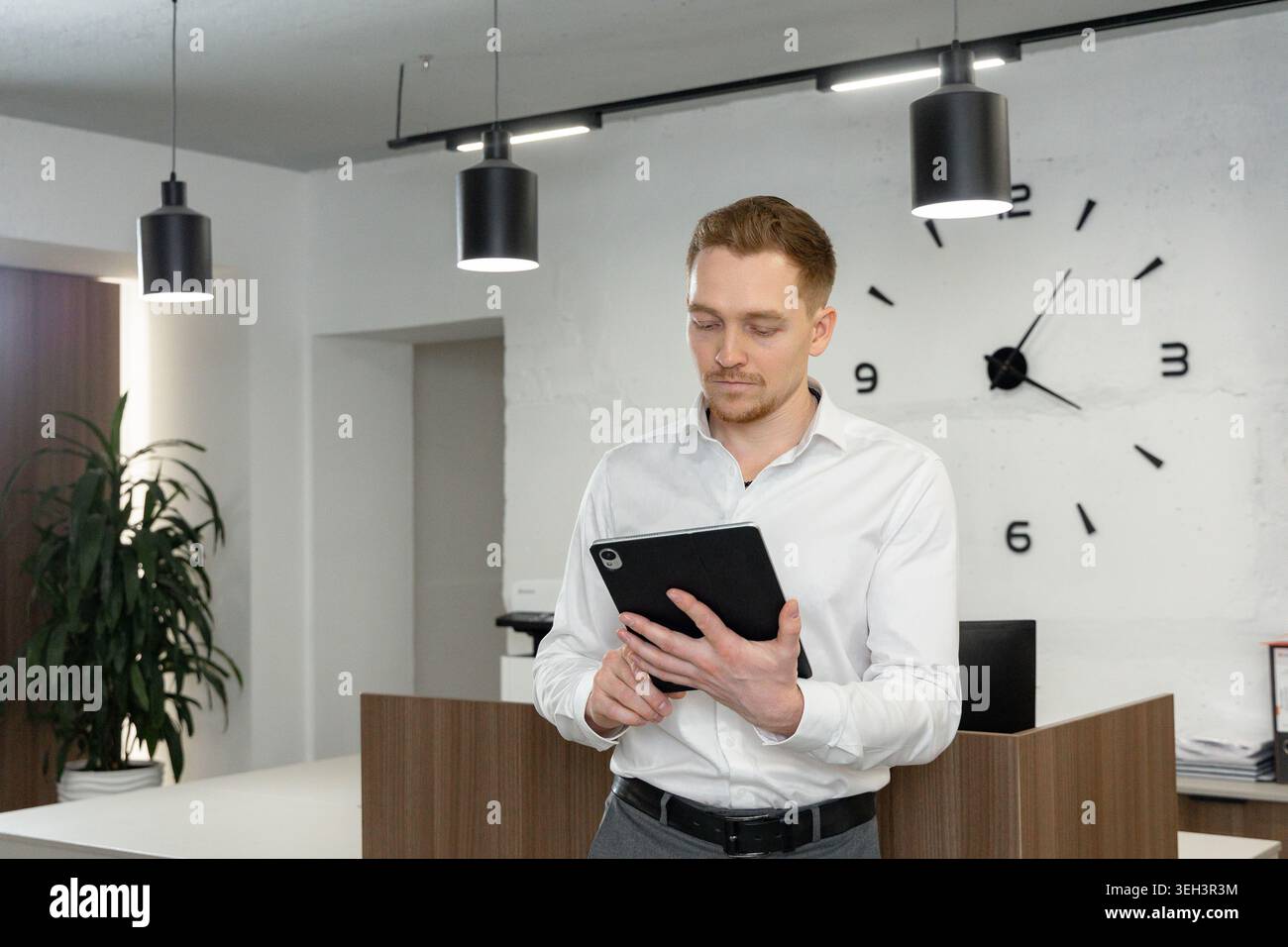 Businessman Using Digital Tablet in Modern Minimal Office Stock Photo