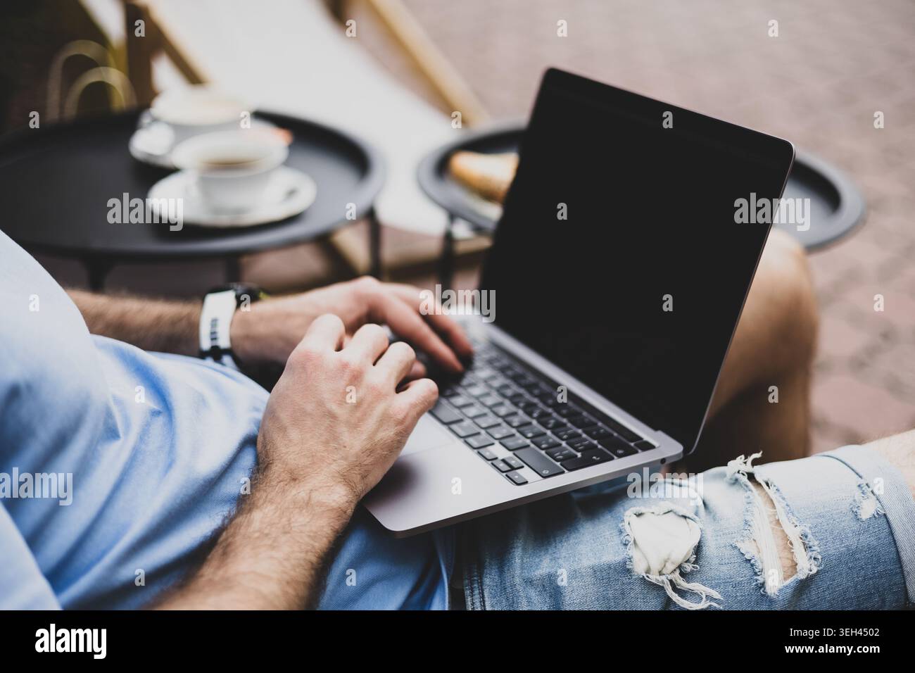 A young man works on a computer on a terrace Stock Photo