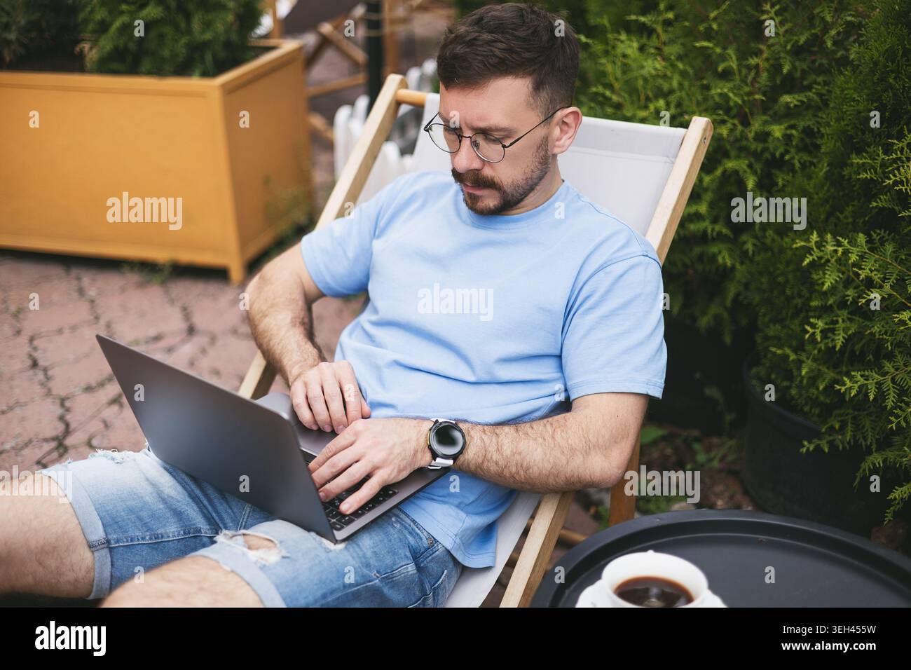A young man works on a computer on a terrace Stock Photo