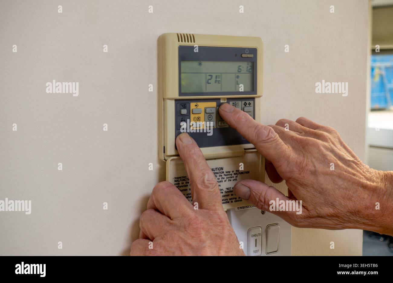 Air conditioning and HVAC engineer programming a very old split system controller. AC contractor interrogating a close control system in an office bui Stock Photo