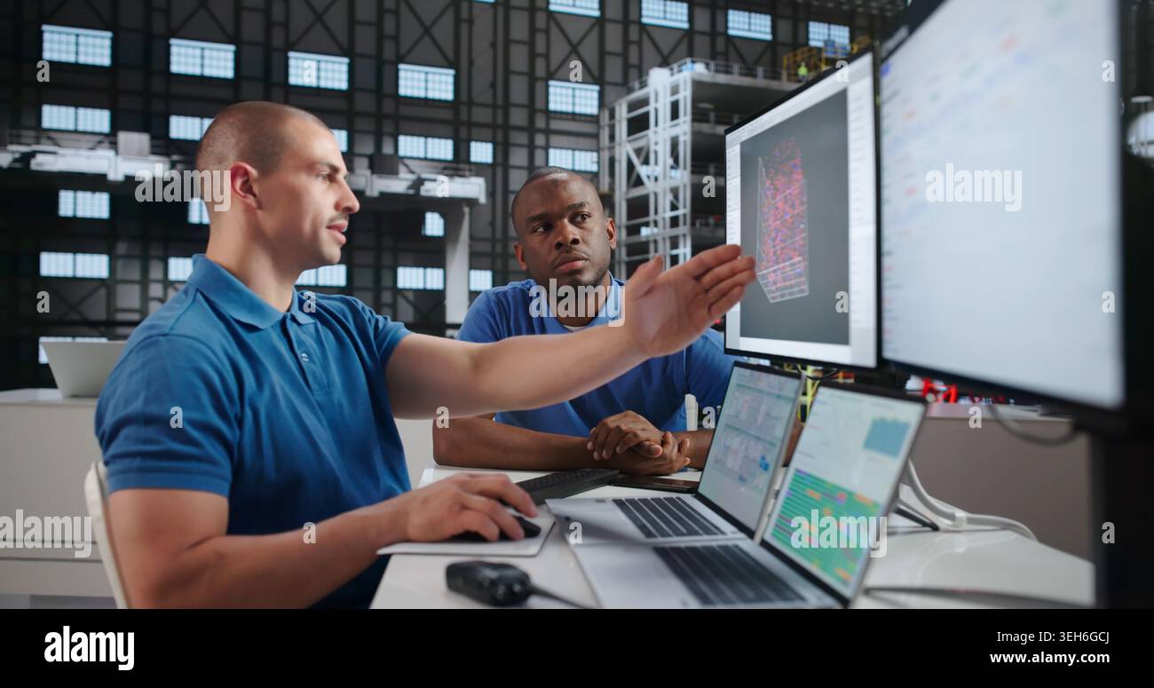 Two Engineers Using Laptops To Design Rockets In Aerospace Lab. Stock Photo