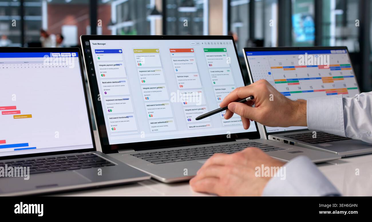 Man At Desk Using Software On Laptop To Organize Project Tasks Efficiently. Stock Photo