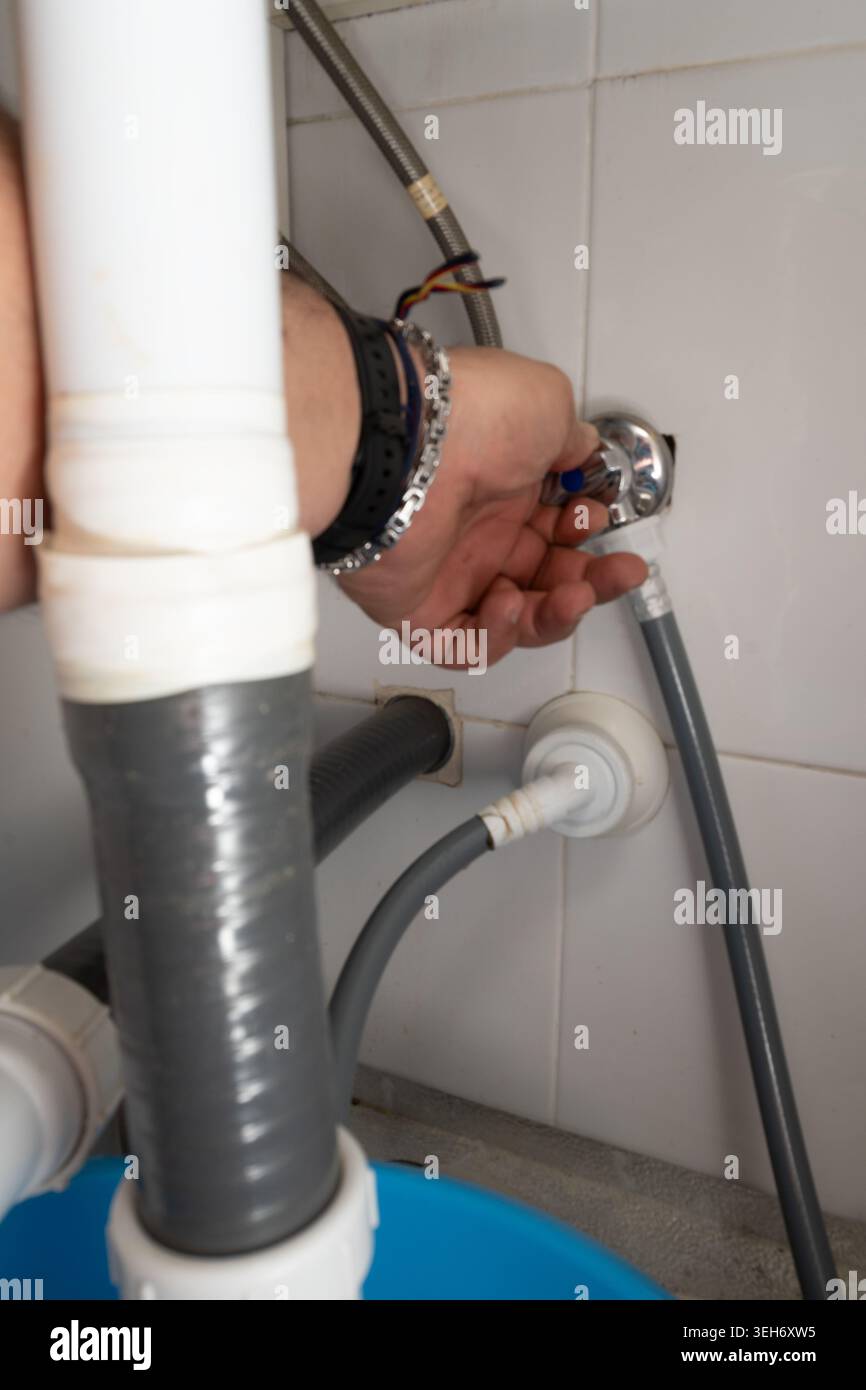 Plumber hand turning valve for pipe connection under a kitchen sink Stock Photo