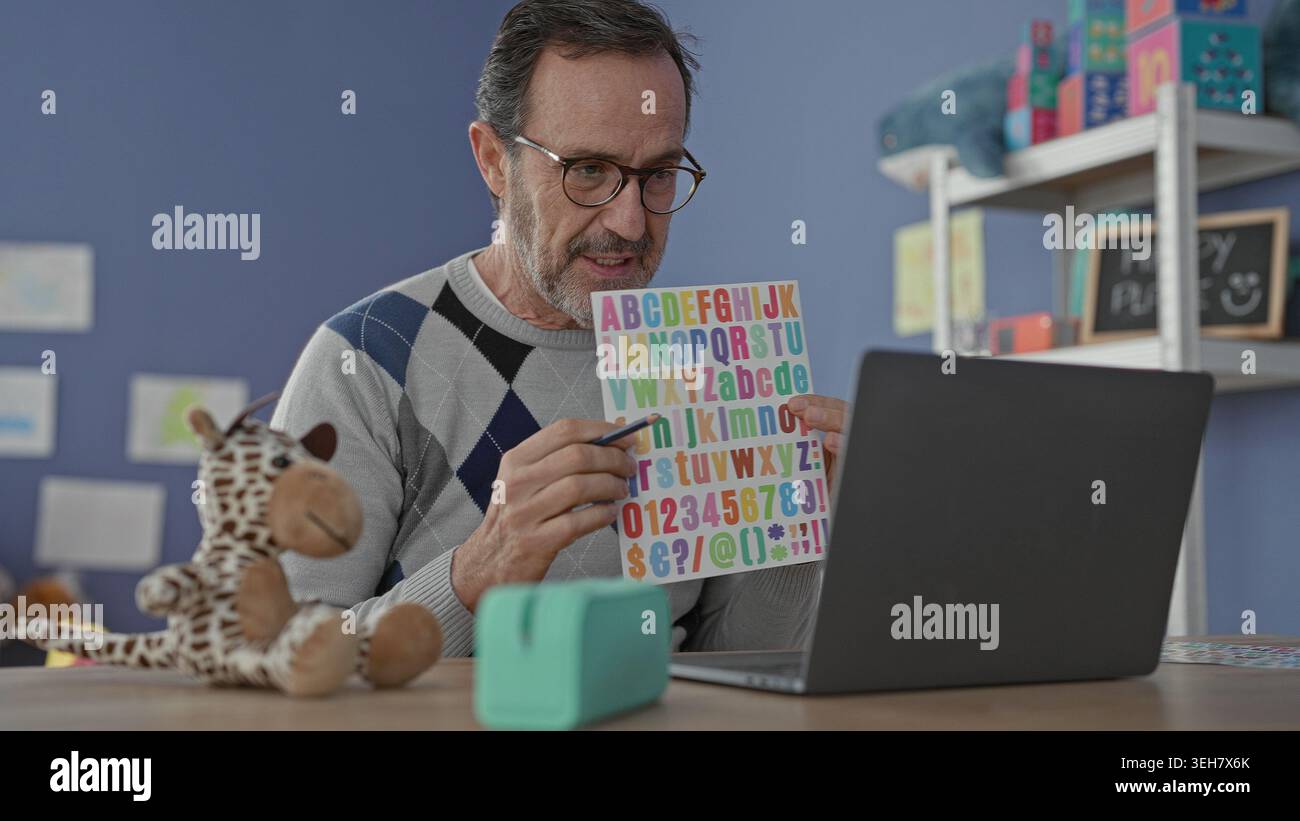 Man teacher holding colorful alphabet card and pointing with pencil at ...