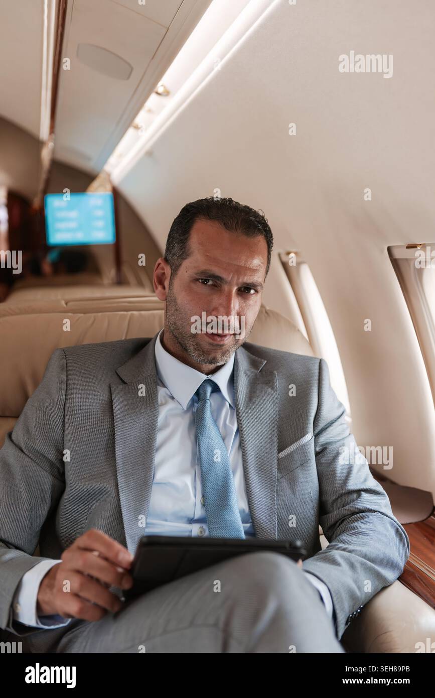Executive businessman working on a tablet in a private jet cabin during business travel Stock Photo