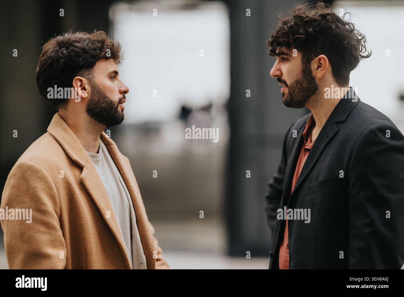 Two men having a serious conversation outdoors in urban casual coats and blazers Stock Photo
