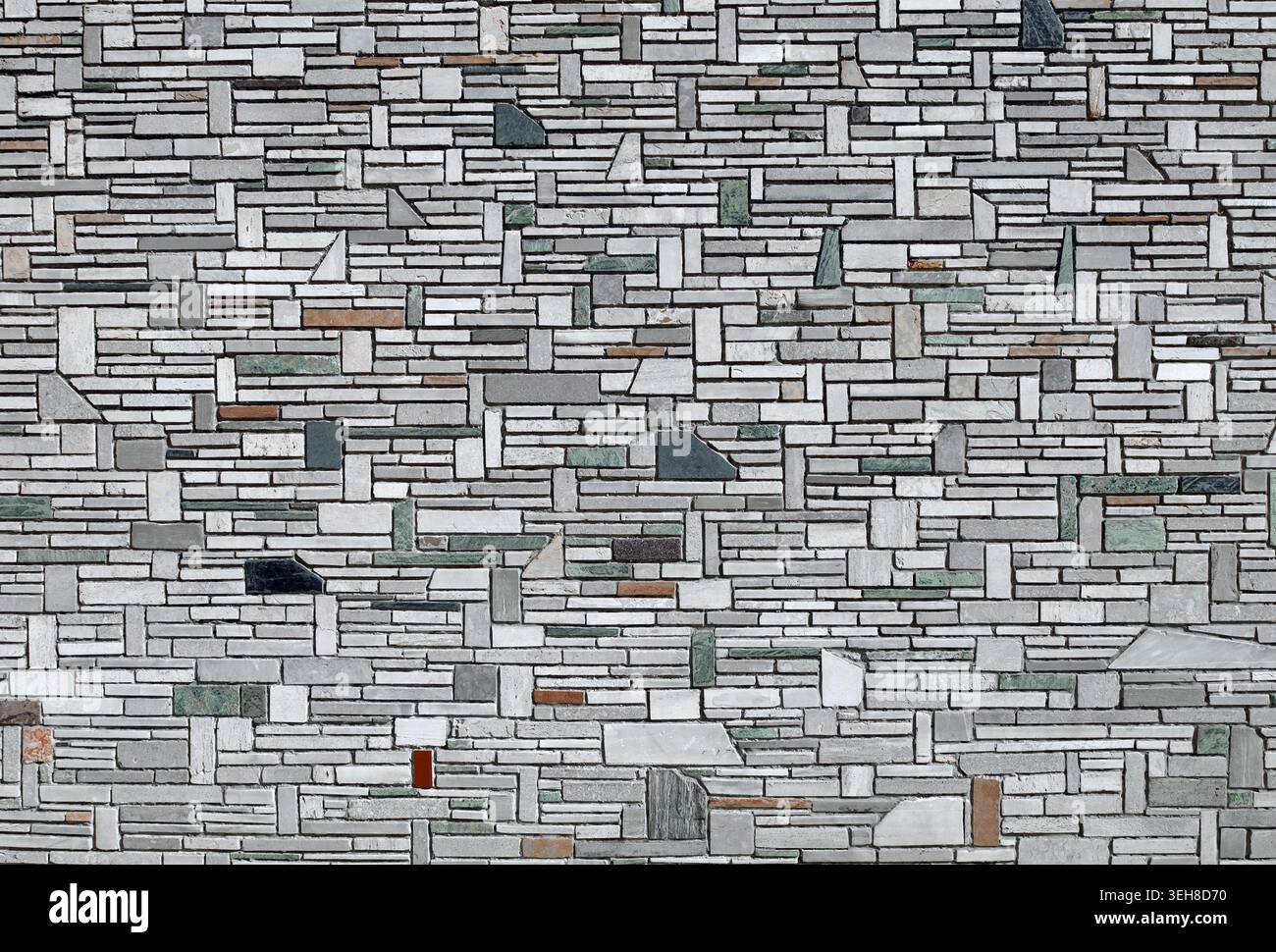 Exterior wall coating made of different size multicolor stone tiles randomly arranged. Background and texture. Stock Photo