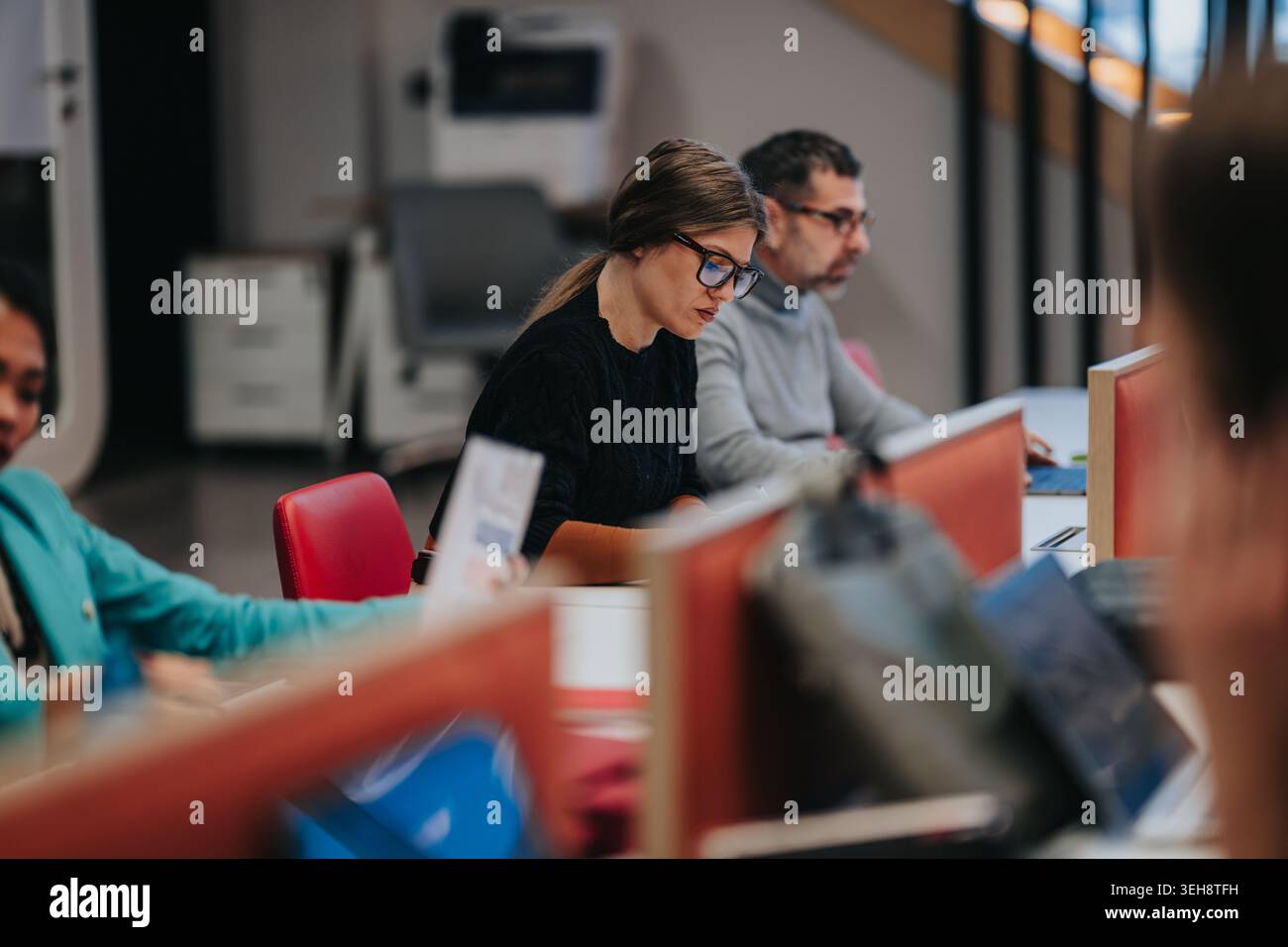 Focused coworkers working at open office desks in a modern business workspace Stock Photo