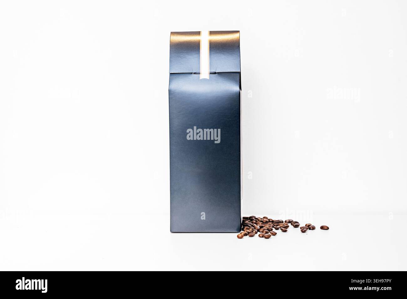 A dark green airtight box with coffee beans on a white surface. Stock Photo