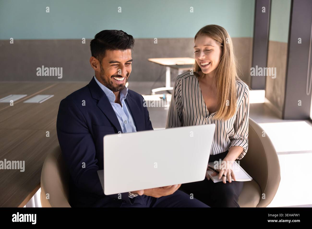 Two smiling coworkers collaborating on laptop in office Stock Photo