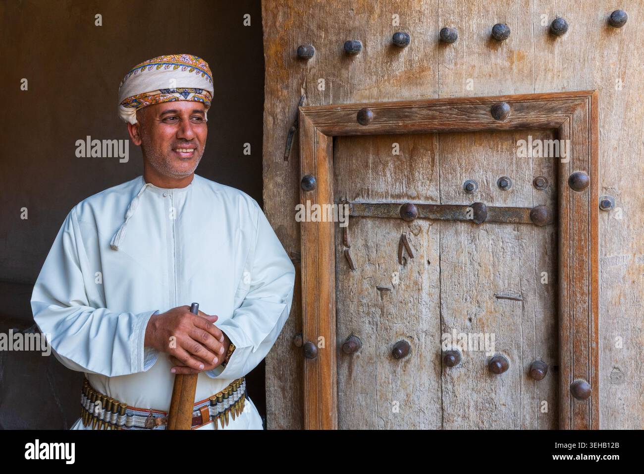 An armed guard in traditional Omani attire with turban (massar) a long ...