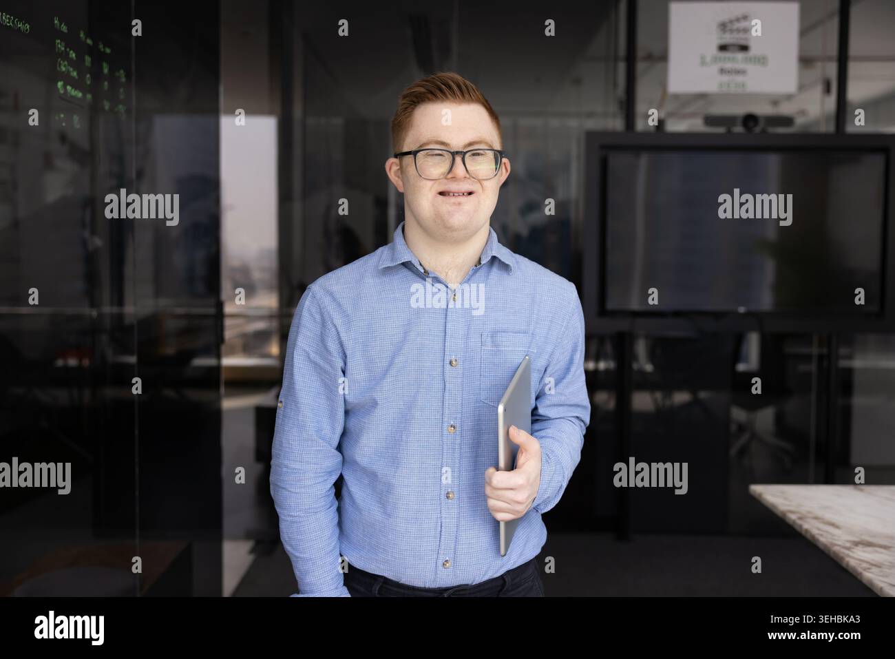 Young man with Down syndrome smiling, posing in office Stock Photo