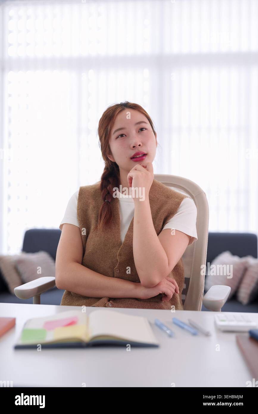 young Asian businesswoman thinking strategy solution planning project at office desk workplace business meeting room Stock Photo
