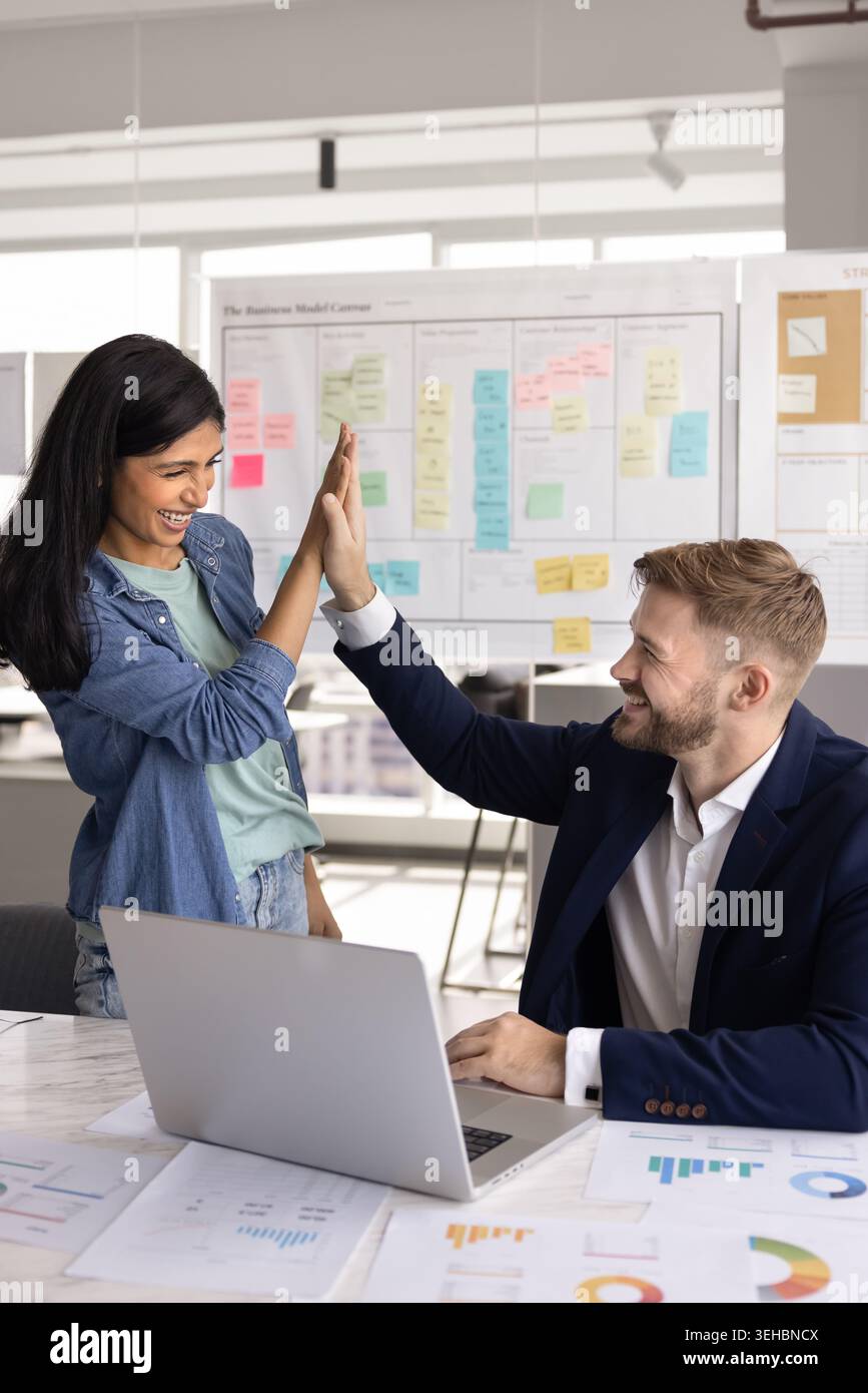 Two laughing workmates giving high five in office Stock Photo