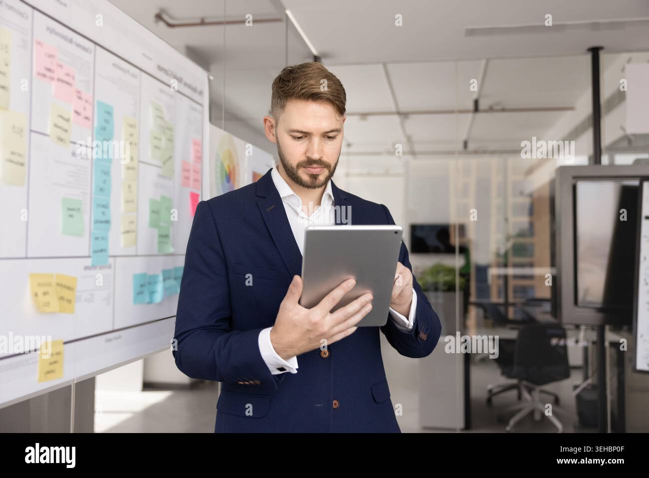 Professional focused man stands in office using digital tablet Stock Photo