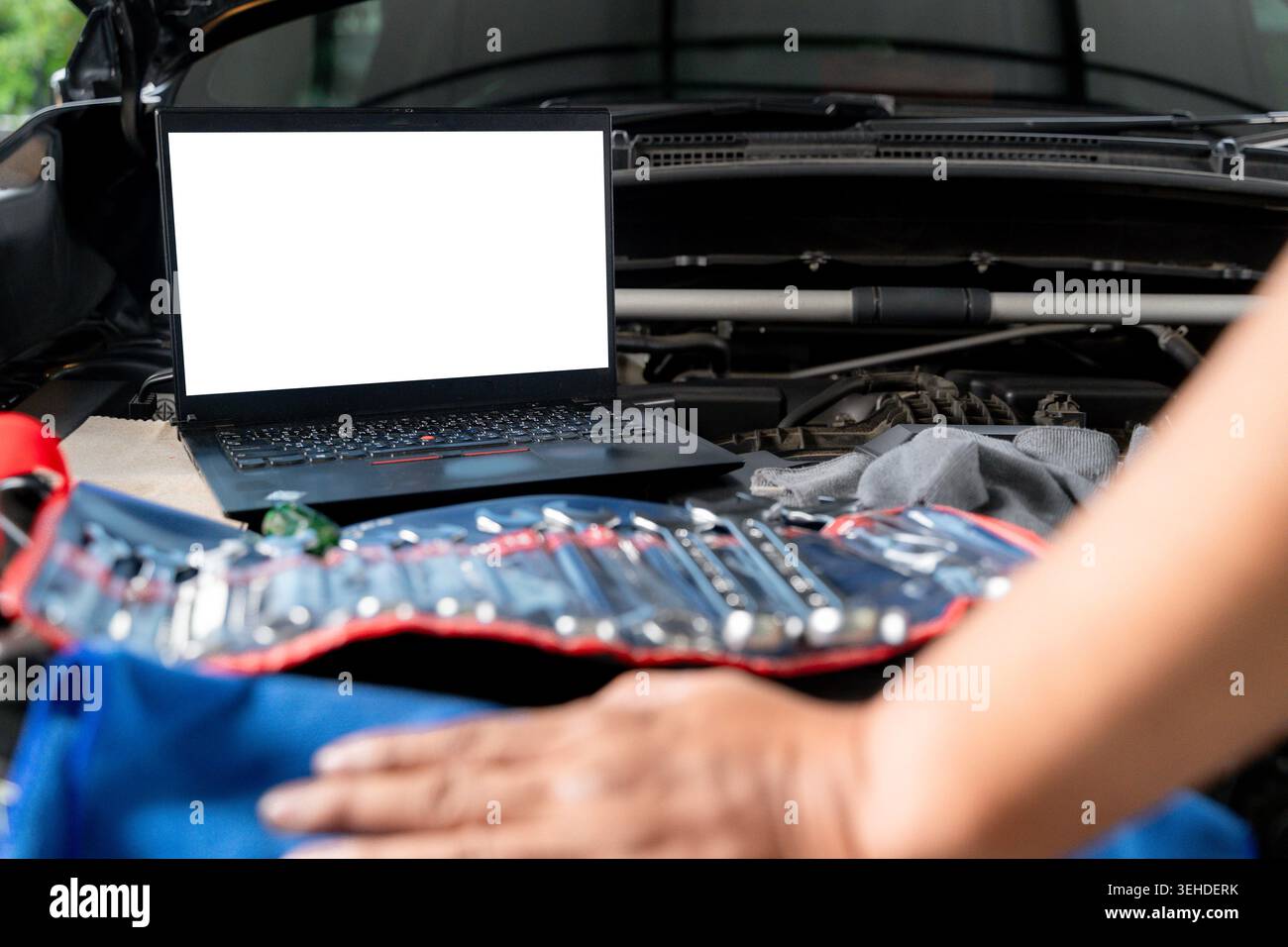 A laptop computer sits on a vehicle's engine block during a computer-aided diagnostic check. Stock Photo