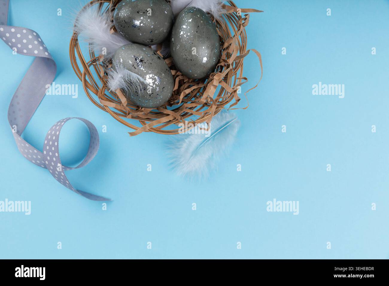 Top view Easter eggs nest with ribbon on blue background Stock Photo