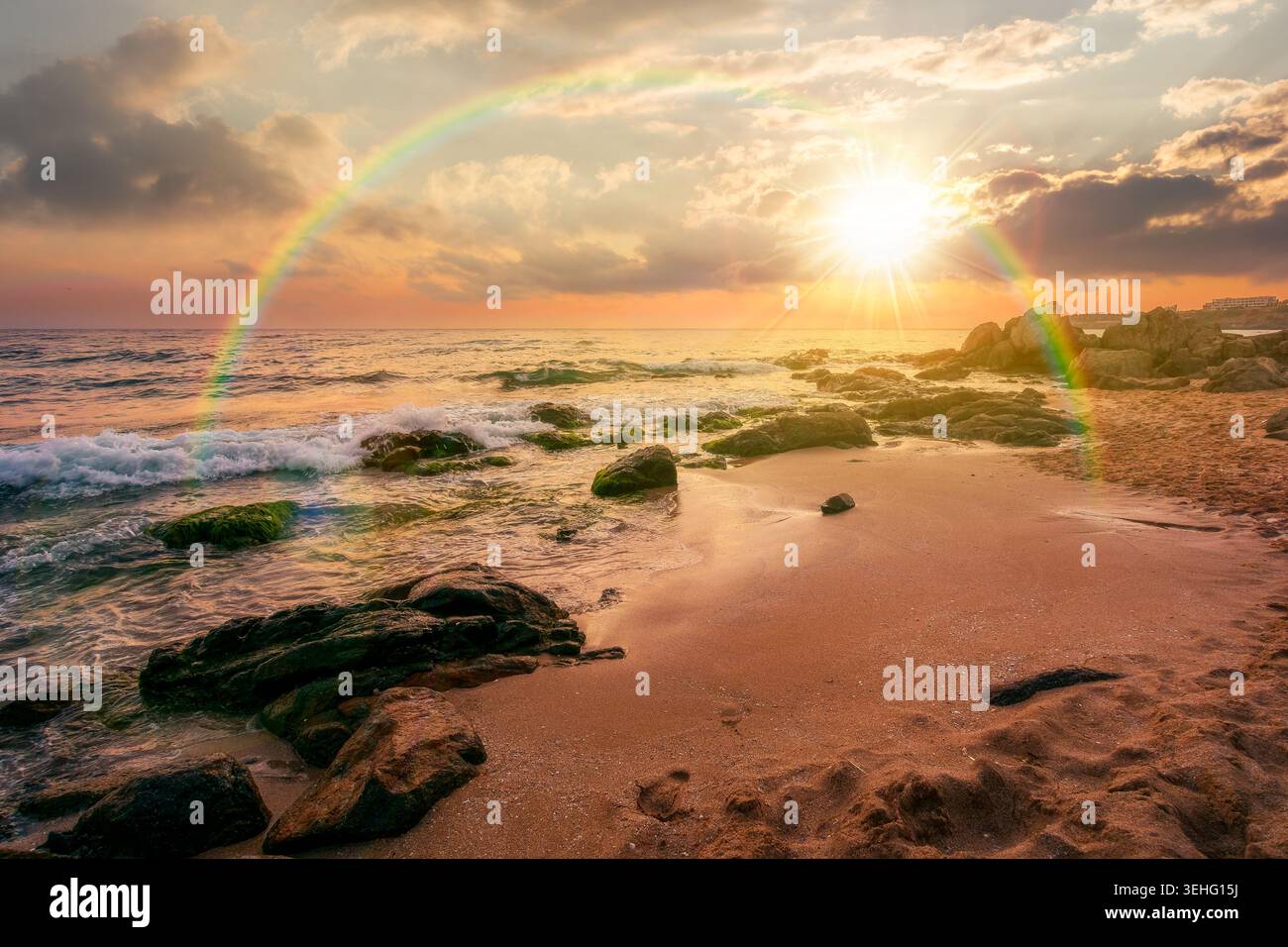 sunset over huge stones on a sandy beach. wonderful summer vacation season at the black sea. calm waves washing the sand shore. nature background with Stock Photo