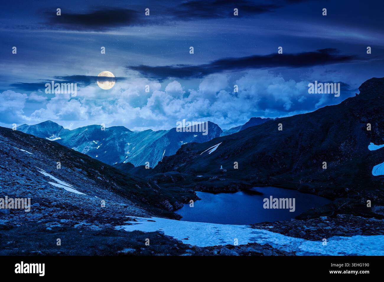 mysterious summer scenery of alpine capra lake with steep slopes at night. fantasy view of transylvania alps, sibiu county. full moon over southern ca Stock Photo