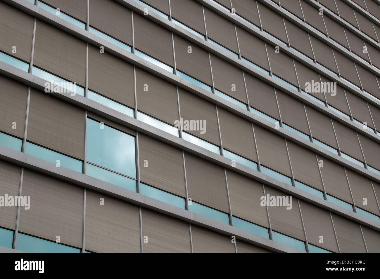 Exterior glass facade of a contemporary office building featuring geometric patterns and shades Stock Photo