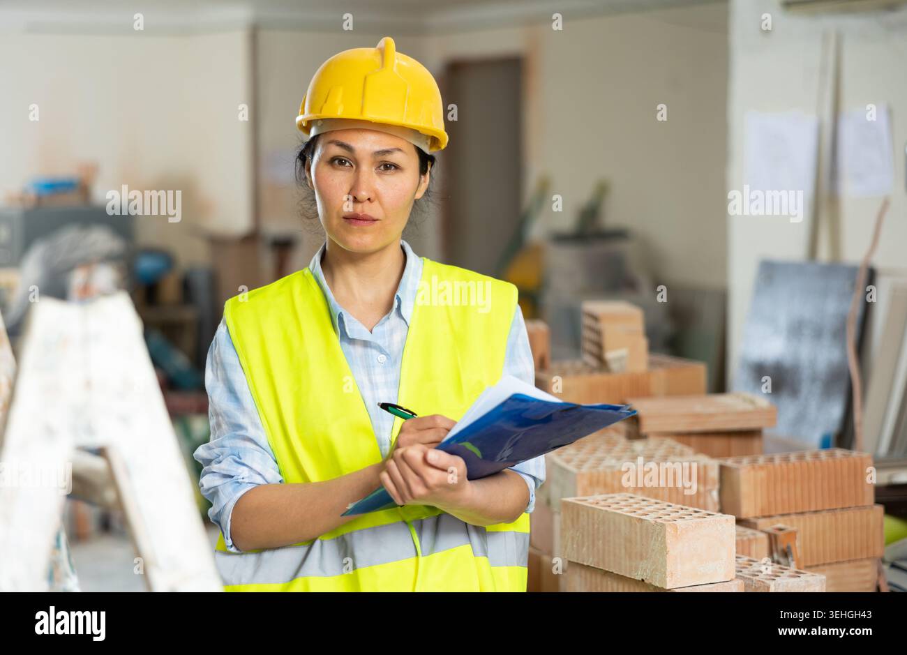 Woman making notes on indoor construction site Stock Photo
