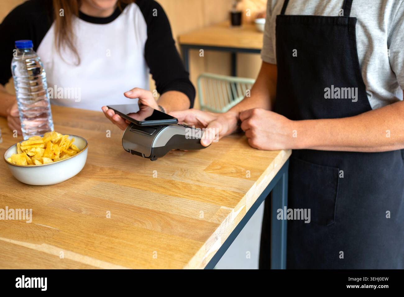 Anonymous customer making contactless payment using smartphone in cafe. Down copy space available. Stock Photo