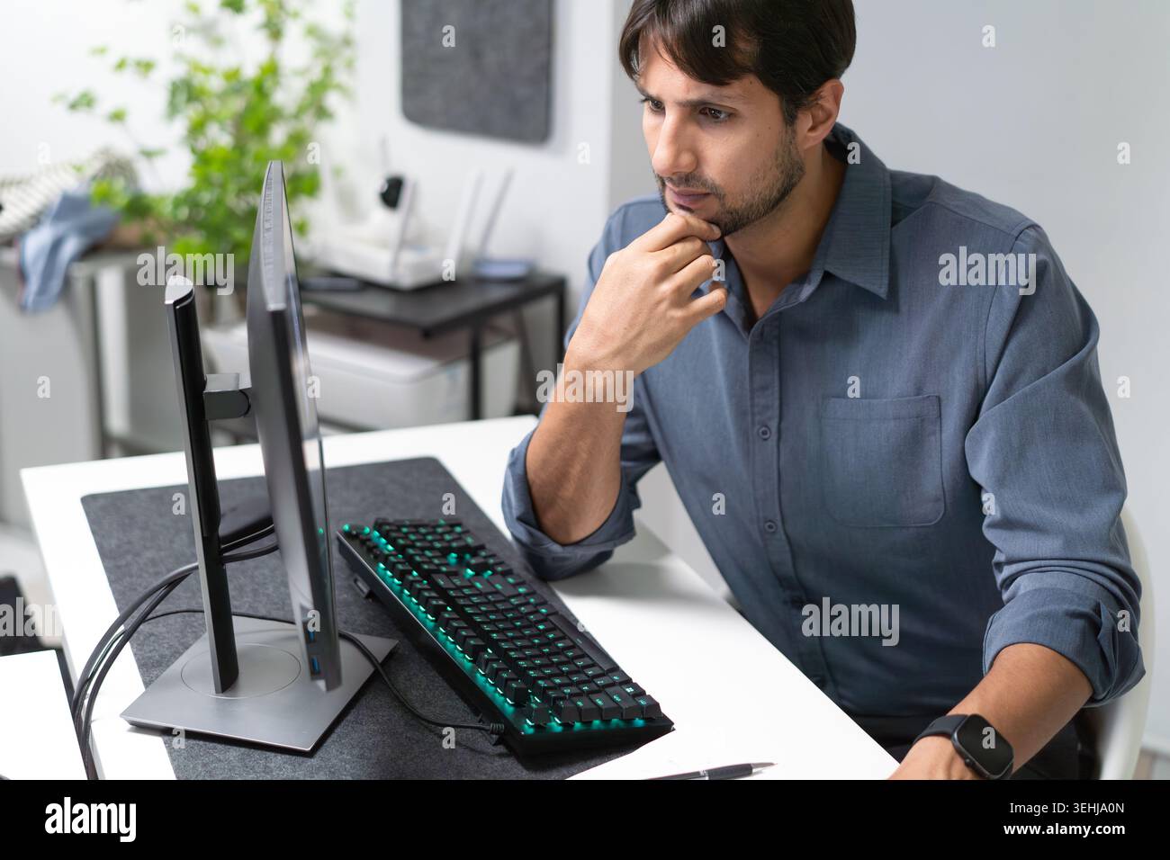 Latino Professional Thinking While Working At Computer In Modern Office Stock Photo