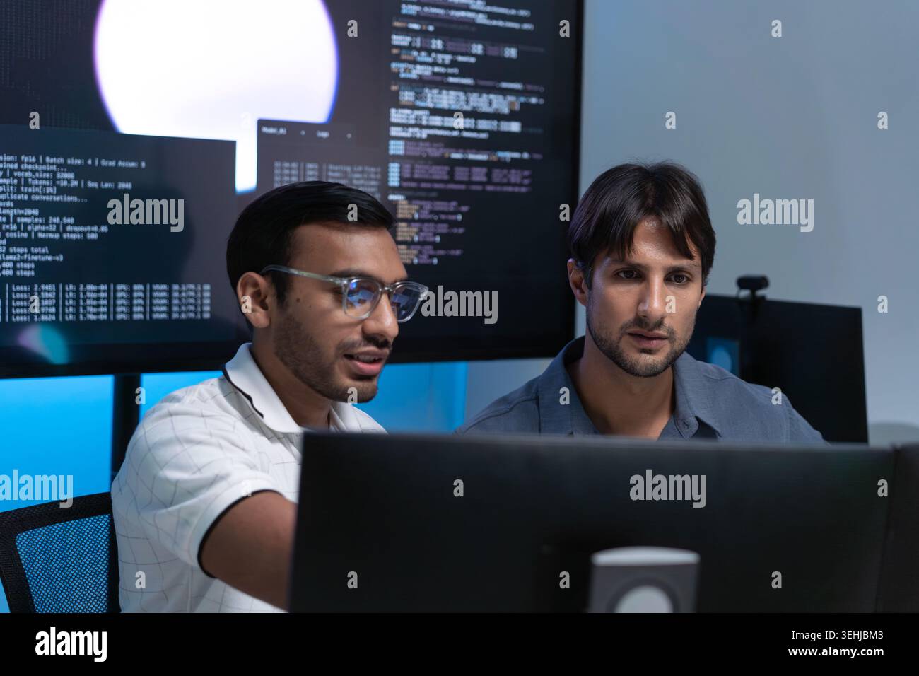 Software Developers Discussing AI Code On Computers In Tech Office Stock Photo