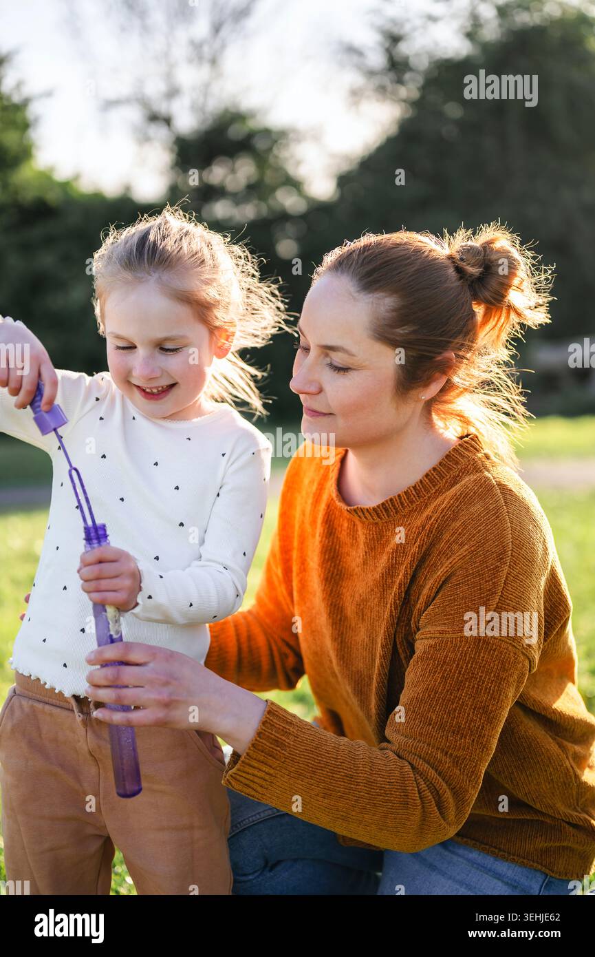Mother and child blowing bubbles in sunlight Stock Photo