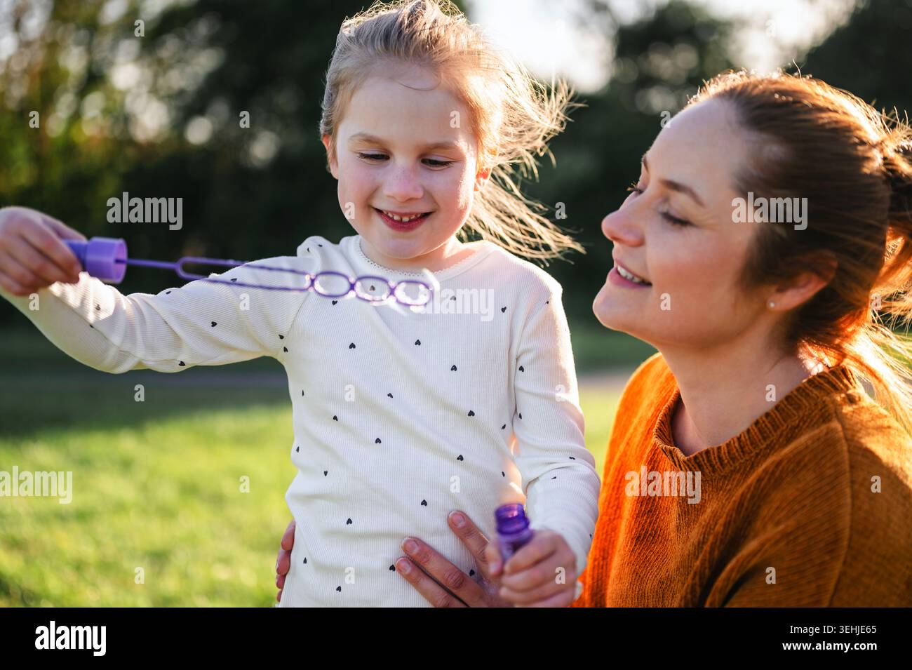 Mother and child blowing bubbles in sunlight Stock Photo