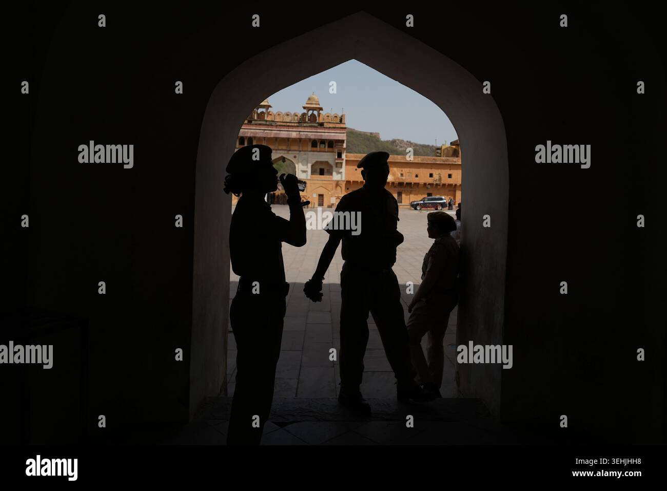 A security official drinks water as she stands in shade with others as ...