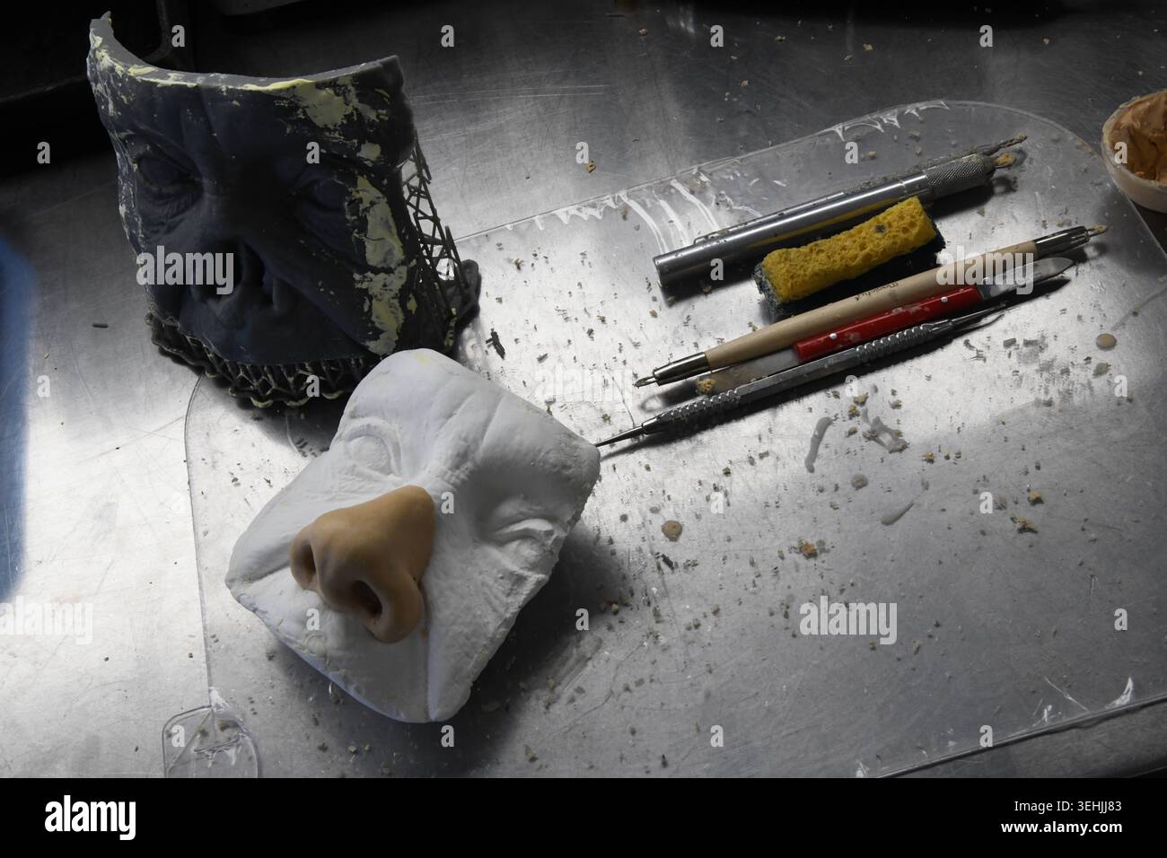 On a workbench, a metal surface supports a dark mold, a white molded ...