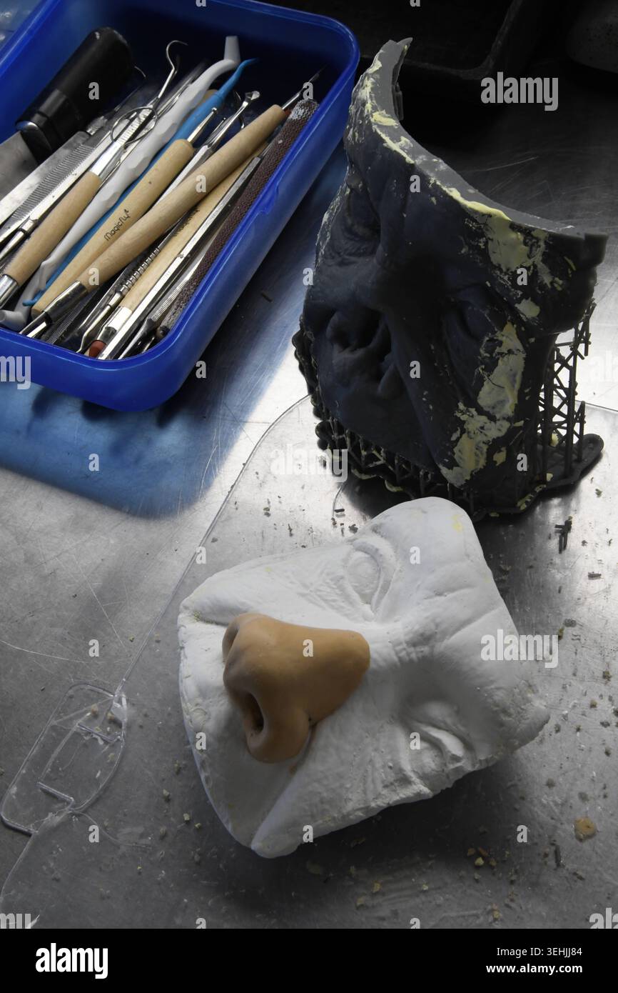 A blue tray of sculpting tools is placed next to a dark grey mold and a ...