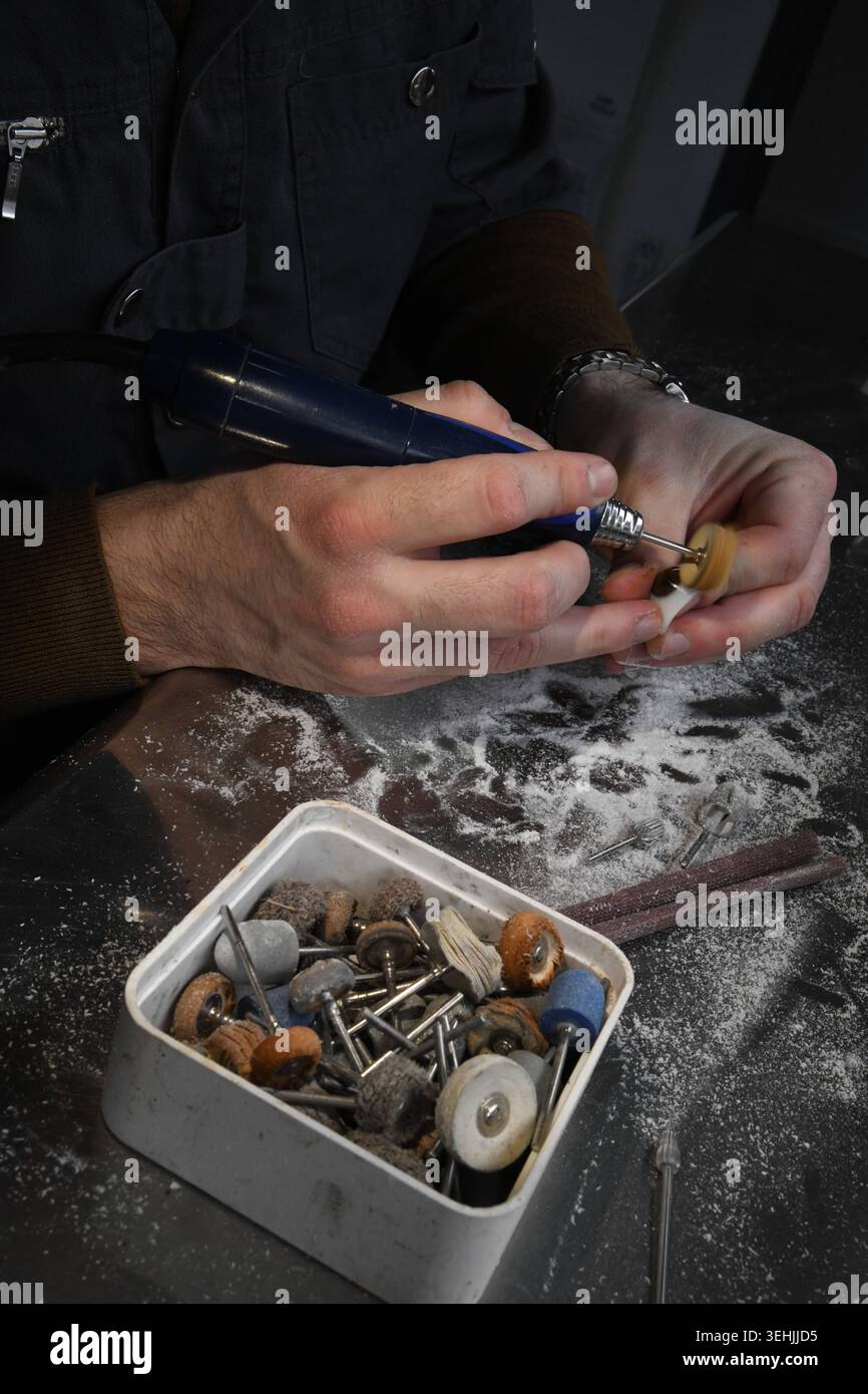 An ophthalmologist using a handheld rotary tool to shape a small object ...