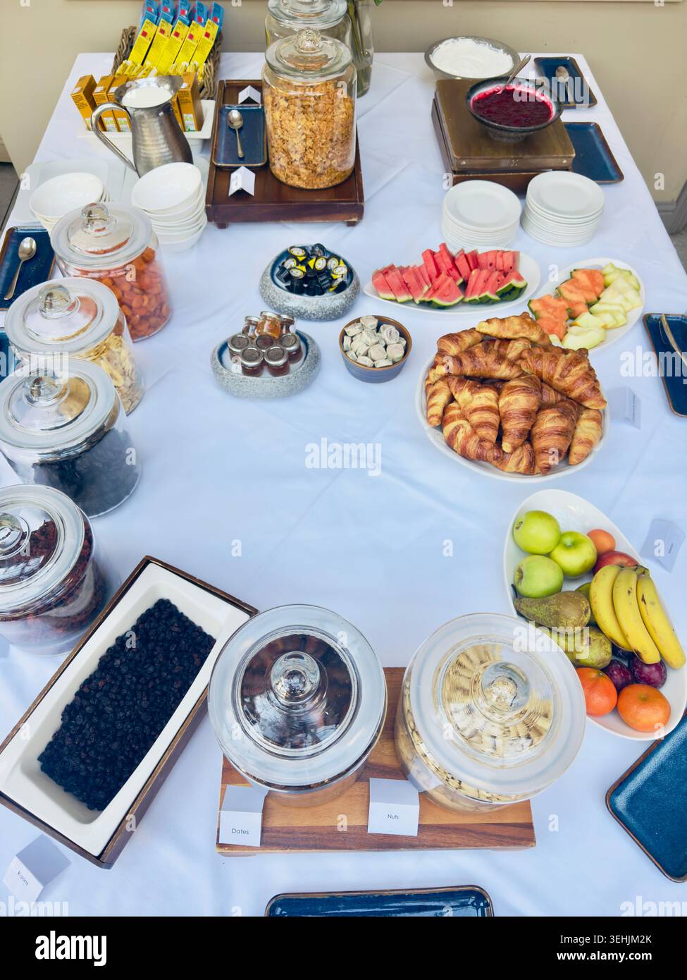 Selection of breakfast foods including croissants, fresh fruit, cereals and preserves displayed on a buffet table Stock Photo