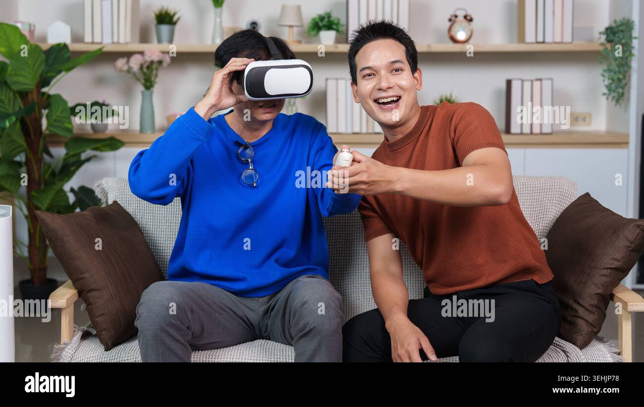Asian senior man experiencing virtual reality with young man at home Stock Photo