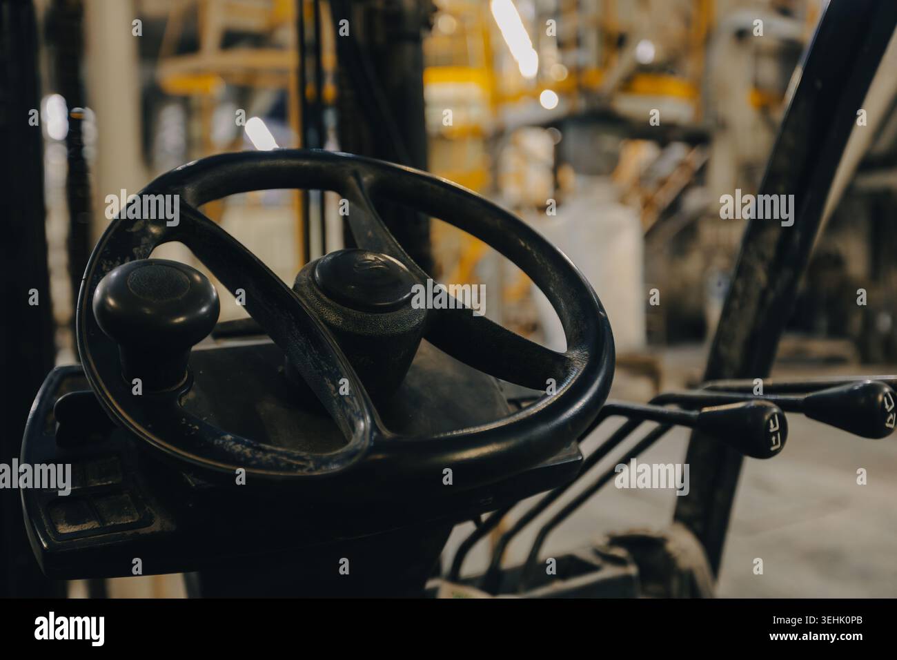 A close up of a forklift operator area showing a black steering wheel ...