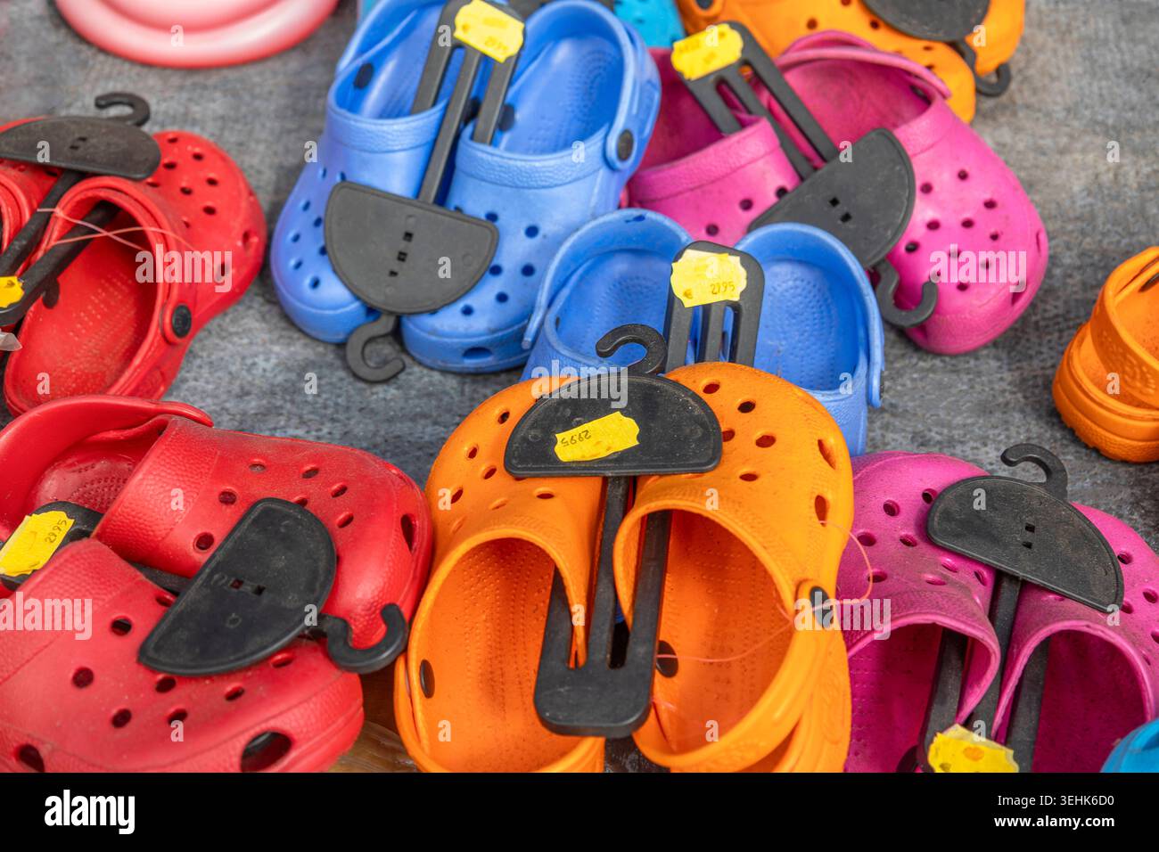 Several pairs of colorful plastic clogs in red, blue, orange, and pink ...