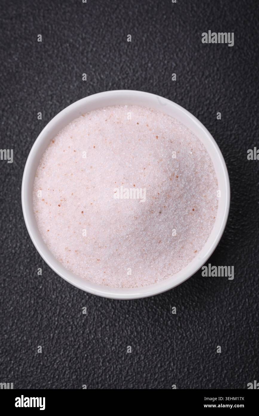 Food, Fine pink Himalayan table salt in a ceramic bowl on a dark concrete background Stock Photo