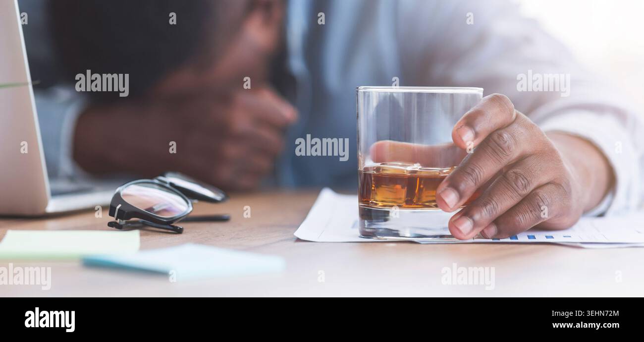Drunk businessman sleeping at workplace with whiskey glass in hand Stock Photo