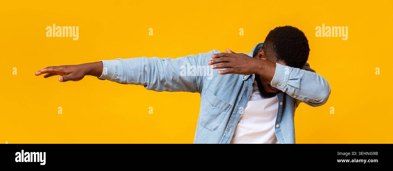 Man throwing dab, making internet meme pose on yellow background Stock Photo