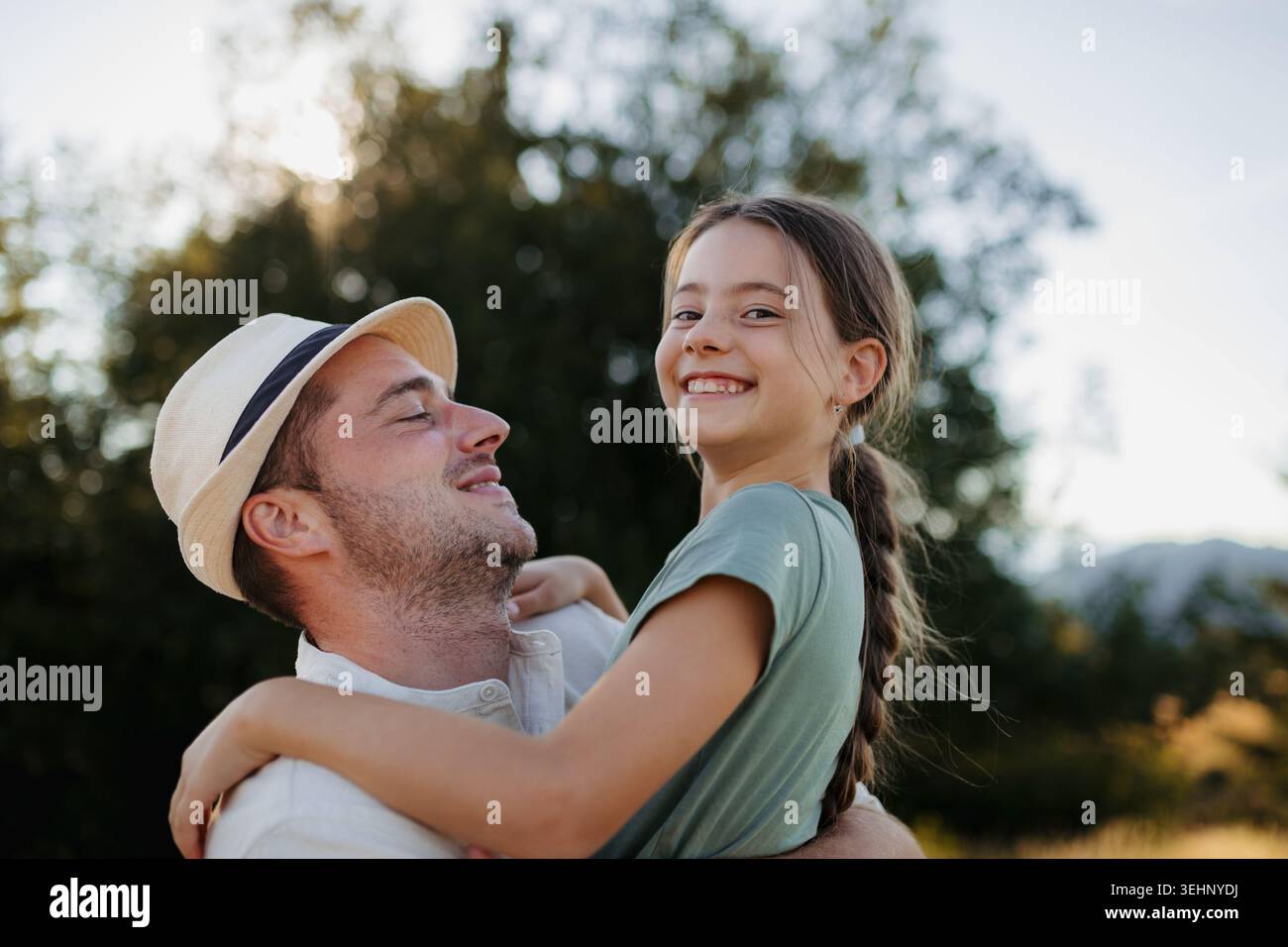 Happy father holding smiling daughter outdoors during family time. Stock Photo