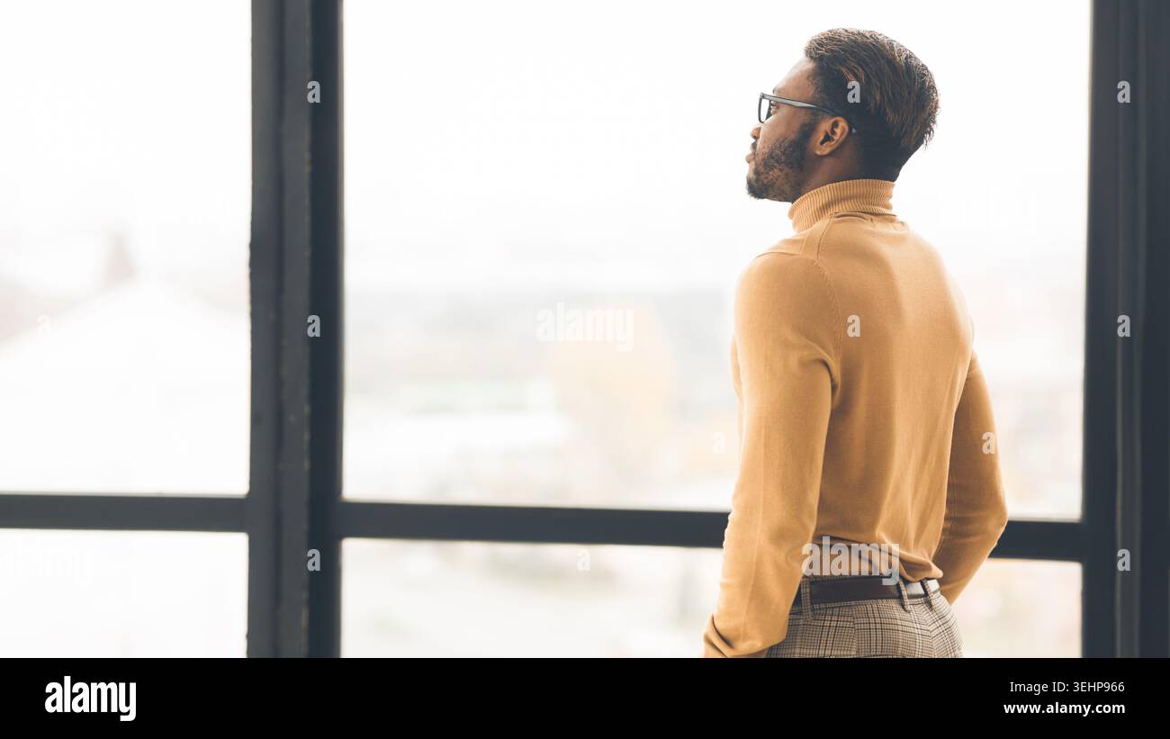 Single afro businessman looking out the window Stock Photo
