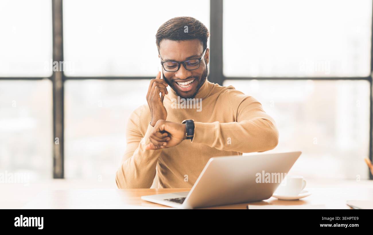African businessman checking time talking on phone Stock Photo