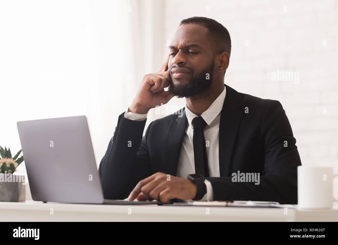 Pensive black businessman working with laptop in office Stock Photo